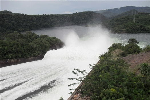 Destinations - Water gushing powerfully through the Akosombo Dam, with surrounding greenery.